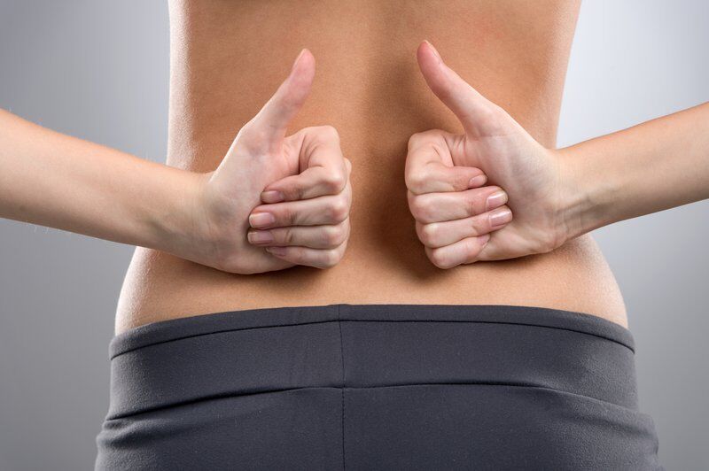 woman back pain with thumbs up after treatment at our pain treatment centers
