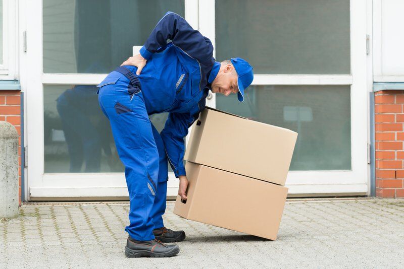 man bending over with back pain picking up boxes