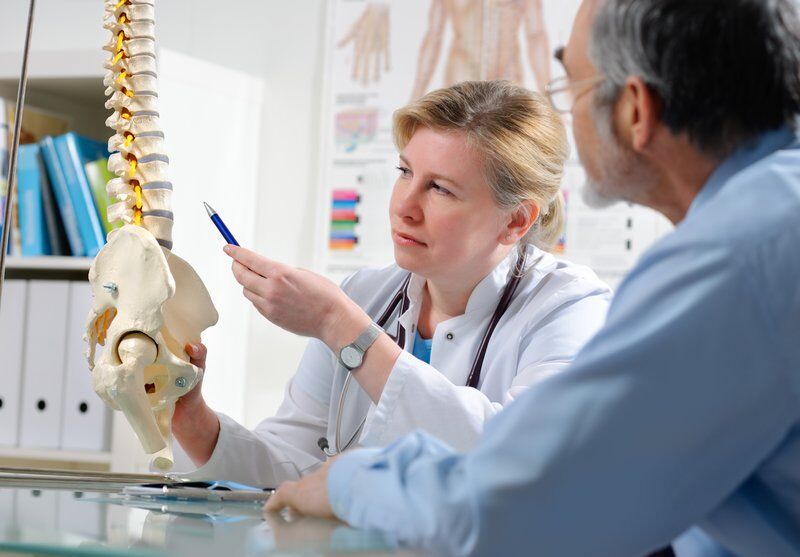 pain management specialist pointing to spine with patient